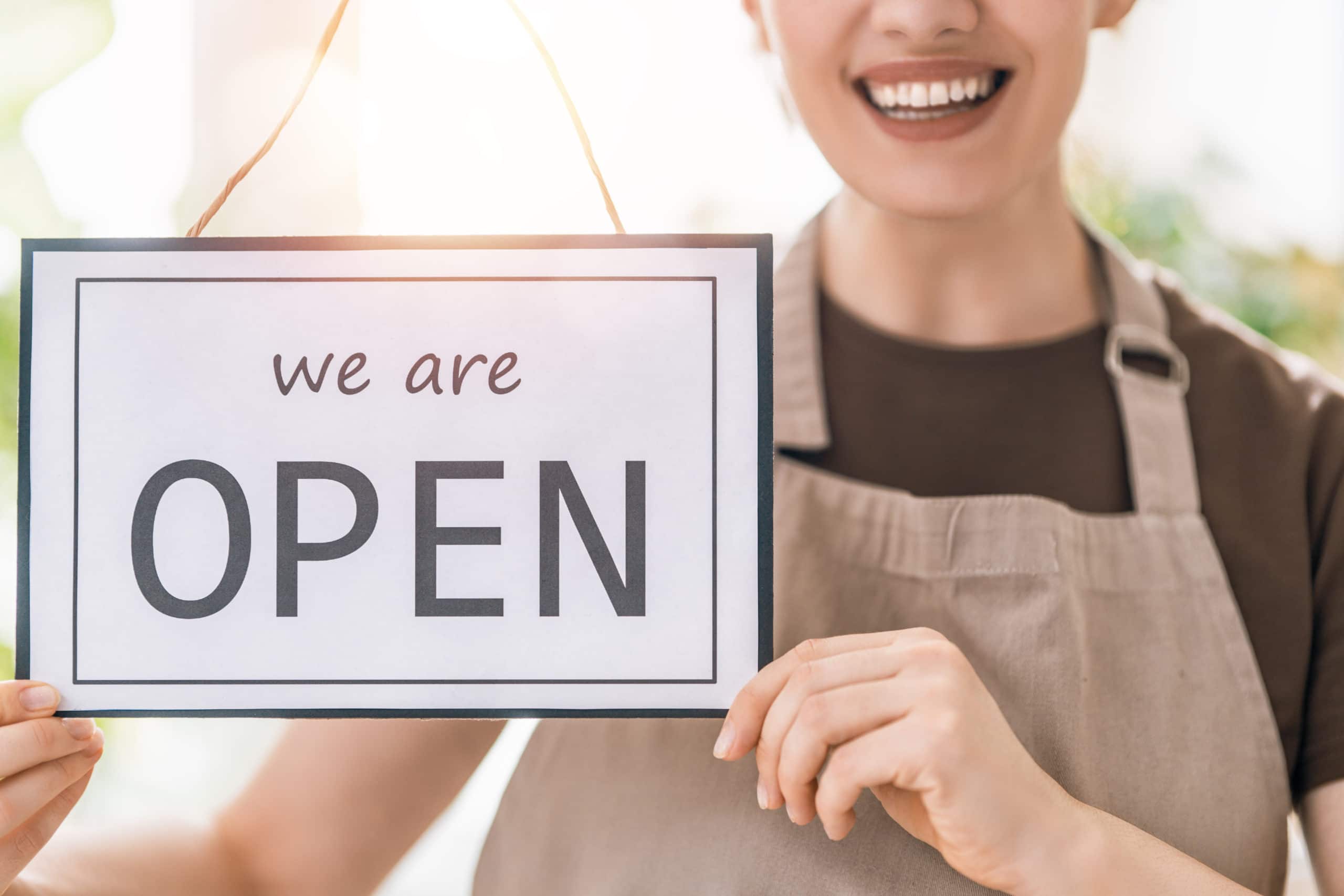 women business owner holding open sign